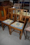 Two early to mid 20th Century oak framed dining chairs having matching drop in tapestry seats
