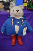 A Gabrielle Designs plush covered Padding Bear soft toy, wearing blue jacket and red wellingtons,