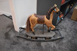A hand decorated wooden Carousel Horse on wood stand with four metal wheels and rocking base, height