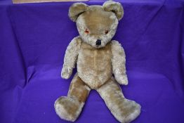 A mid 20th century straw filled yellow plush teddy bear having plastic eyes, stitched nose and