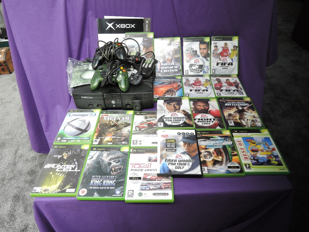 A Microsoft Xbox console with two controllers, power cable, remote control and instruction booklet