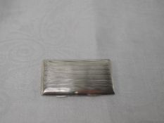 A silver card case of rectangular form having spring hinge, engine turned stripe decoration and gilt