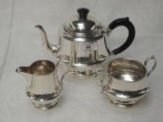 A silver three piece breakfast tea set of plain circular form having loop handles and indented