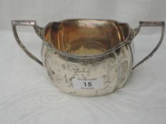 A silver sugar bowl of plain canted form having engraved decoration to rim and base, Sheffield 1930,