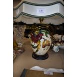 A Moorcroft Anna lily table lamp with shade having lily design in green,red and ochre on cream