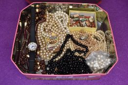 A vintage tin containing a selection of broken strings of beads and simulated pearls etc