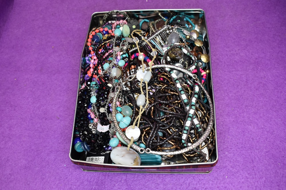 A tin of costume jewellery necklaces of various forms