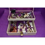 A jewellery box containing a selection of costume jewellery including clip and stud earrings, native
