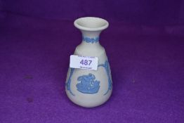 A small Wedgwood vase having blue relief pattern on white ground.