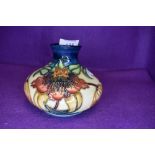 A Moorcroft Tiger lily vase of squat form having cream and blue ground with lily pattern in ochre