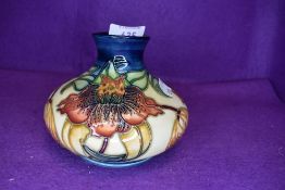 A Moorcroft Tiger lily vase of squat form having cream and blue ground with lily pattern in ochre