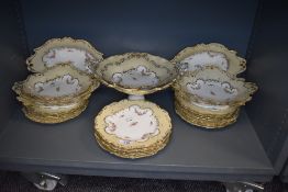 A selection of antique porcelain plates and serving dishes in a Rockingham design having cream and