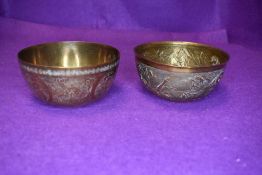 Two oriental brass bowls having embossed patterns one with storks and bamboo the other with