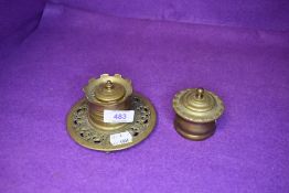 Two brass ink wells, one having glass liner the other having intricate pattern to base.