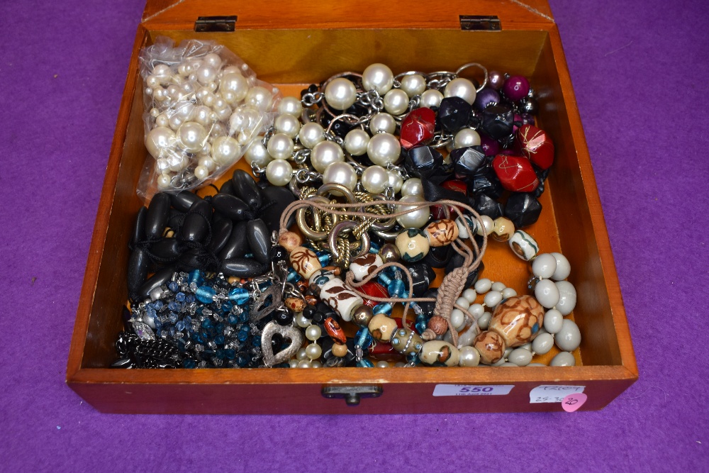 A small wooden display box containing a selection of costume jewellery necklaces, including