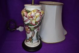 A Moorcroft lamp base having pale pink Magnolia type design on cream ground.