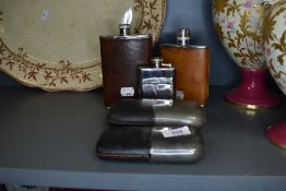 An assortment of vintage hip flasks, various styles and sizes.