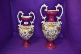 Two vintage handled vases or urns in pink and cream with hand tinted floral pattern and gilt