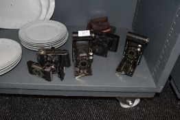 An assortment of vintage cameras including Ensign Midget, two vest pocket Kodaks, Prontor II and