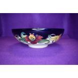 A Moorcroft Tiger lily fruit bowl having cream and blue ground with lily pattern in ochre,green