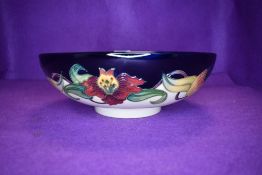 A Moorcroft Tiger lily fruit bowl having cream and blue ground with lily pattern in ochre,green