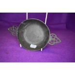 A traditional pewter porringer bowl with pierced handles