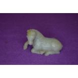 A Chinese Nephrite or Jade figure of a resting horse in a pale green tail being damaged otherwise