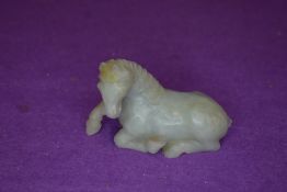 A Chinese Nephrite or Jade figure of a resting horse in a pale green tail being damaged otherwise