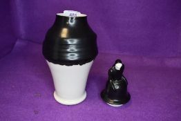 A mid century porcelain storage container having grotesque hooded figure to lid with two tone