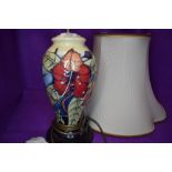 A Moorcroft lamp base having lily and vine type design on cream ground.