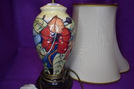 A Moorcroft lamp base having lily and vine type design on cream ground.