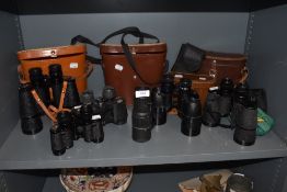 A collection of vintage binoculars, some with cases, including Zenith and Denhill.