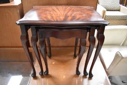 An early 20th Century flame mahogany nest of table having shaped top and cabriole legs