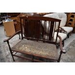 An Edwardian mahogany settee having line and crown inlay , shaped arms and turned legs, upholstery a