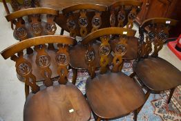 A set of seven Ercol dark stained 'fleur de lys' back chairs