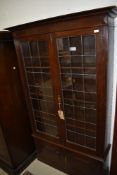 A late 19th/early 20th Century oak display cabinet having leaded glass display over double