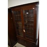 A late 19th/early 20th Century oak display cabinet having leaded glass display over double