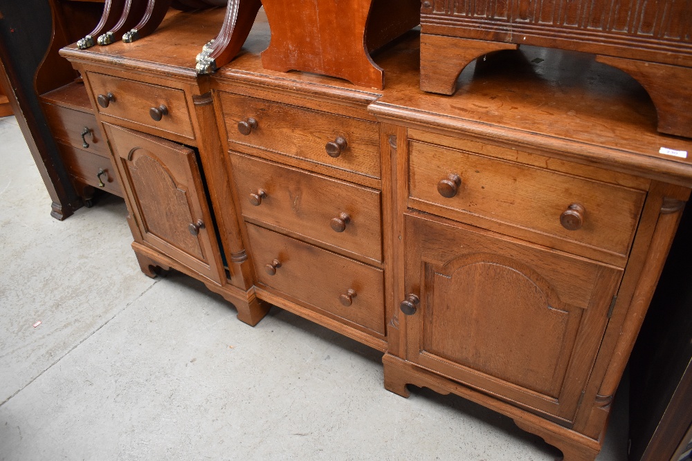 A traditional solid oak sideboard having recessed three drawer centre section flanked by drawers and