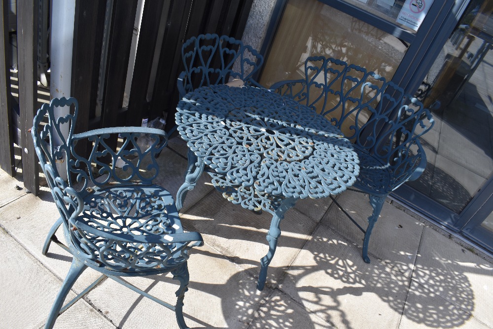 A selection of heavy cast metal garden furniture including double bench table and two chairs