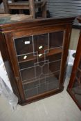 An early 20th Century stained frame corner wall display having leaded glass door