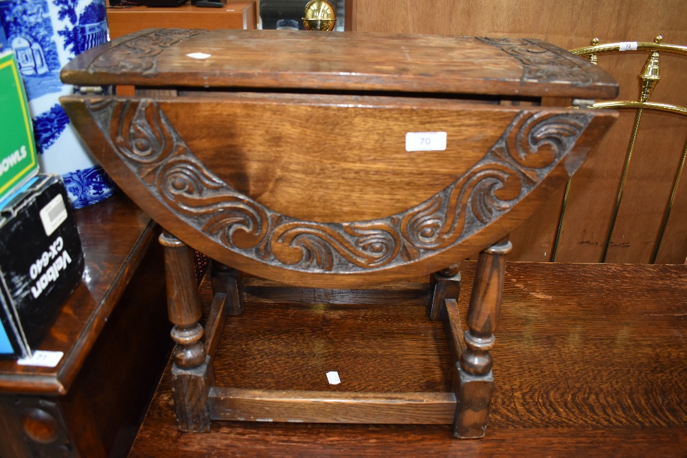 A traditional oak drop leaf occasional table having part carved top