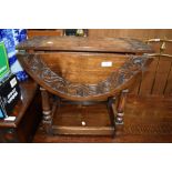 A traditional oak drop leaf occasional table having part carved top