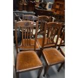 A set of four early to mid 20th Century oak dining chairs, badly wormed
