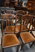 A set of four early to mid 20th Century oak dining chairs, badly wormed