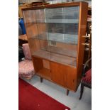 A vintage teak display cabinet having glazed upper section over cupboard, with sliding doors,