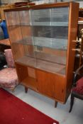 A vintage teak display cabinet having glazed upper section over cupboard, with sliding doors,