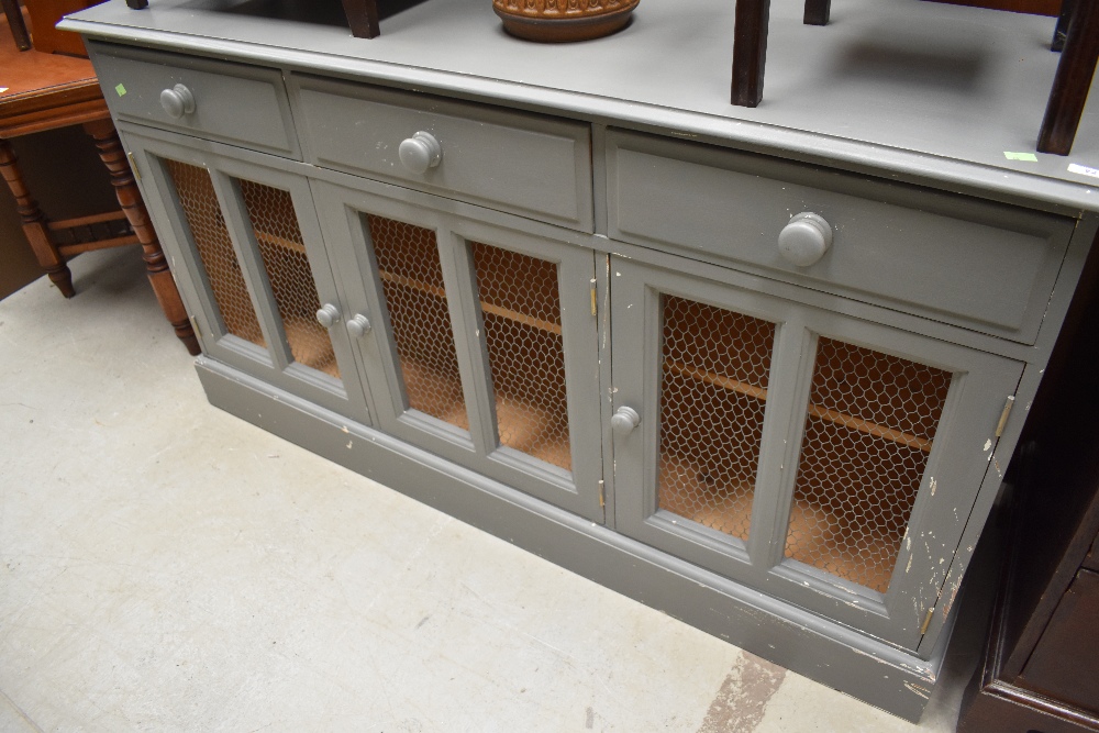 A grey painted sideboard having three frieze drawers over triple cupboard, having mesh panel fronts,