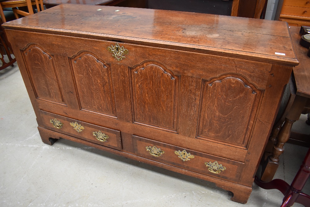 A Georgian oak 4 panel kist having drawer base, brass handles and escutcheons, bracket feet,