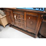 An early 20th Century oak sideboard having ledge back, three central drawers flanked by cupboard,