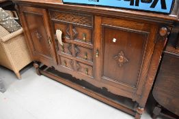 An early 20th Century oak sideboard having ledge back, three central drawers flanked by cupboard,